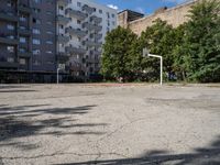 an empty basketball court is seen in this photograph from the corner in front of an apartment complex