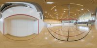 an empty and empty indoor gym with multiple courts and red and white lines on the floor