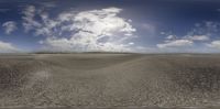 a wide view of an empty beach with low clouds in the sky and there is a man that can be seen