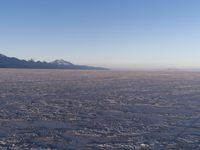 there is a picture taken from the airplane of an empty beach covered in ice with mountains in the distance