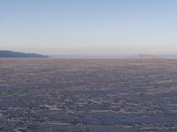 there is a picture taken from the airplane of an empty beach covered in ice with mountains in the distance