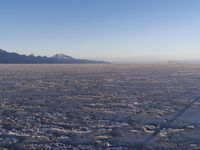 there is a picture taken from the airplane of an empty beach covered in ice with mountains in the distance