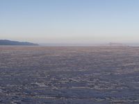 there is a picture taken from the airplane of an empty beach covered in ice with mountains in the distance