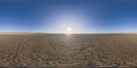 the sun shines behind the horizon of an empty beach with sand and water on a clear, blue day