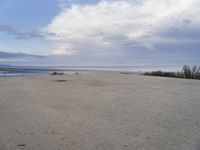 a lone skateboard parked at the edge of an empty beach during the day in cloudy conditions