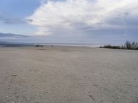 a lone skateboard parked at the edge of an empty beach during the day in cloudy conditions