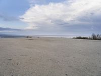 a lone skateboard parked at the edge of an empty beach during the day in cloudy conditions