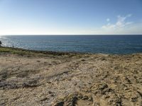 a beach is empty with rocks and some water and birds flying above it on a clear, sunny day