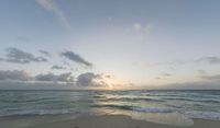 the beach is empty during sunset as the sun sets in the distance behind the horizon