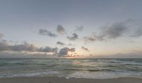 the beach is empty during sunset as the sun sets in the distance behind the horizon