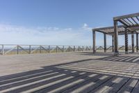 an empty bench is located on a boardwalk by the water, with clear skies and the sky