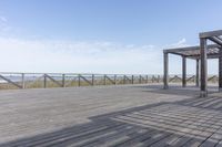 an empty bench is located on a boardwalk by the water, with clear skies and the sky