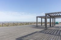 an empty bench is located on a boardwalk by the water, with clear skies and the sky