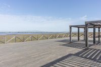 an empty bench is located on a boardwalk by the water, with clear skies and the sky