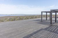 an empty bench is located on a boardwalk by the water, with clear skies and the sky