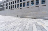 a empty bench sitting in front of an office building next to a large brick walkway