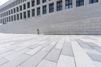 a empty bench sitting in front of an office building next to a large brick walkway