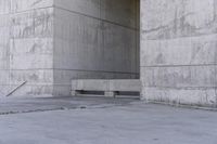 there is a empty bench outside of an old building with concrete walls and cement flooring