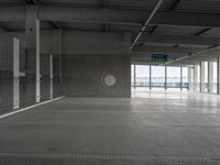 an empty building with concrete floors, two circular windows and a window in the center