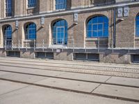 the building has many windows on it and is mostly empty with no people walking on the sidewalk