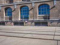 the building has many windows on it and is mostly empty with no people walking on the sidewalk