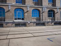 the building has many windows on it and is mostly empty with no people walking on the sidewalk