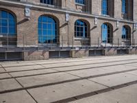 the building has many windows on it and is mostly empty with no people walking on the sidewalk