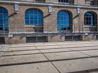 the building has many windows on it and is mostly empty with no people walking on the sidewalk