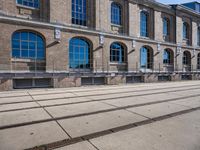 the building has many windows on it and is mostly empty with no people walking on the sidewalk