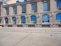 the building has many windows on it and is mostly empty with no people walking on the sidewalk