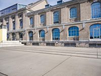 the building has many windows on it and is mostly empty with no people walking on the sidewalk