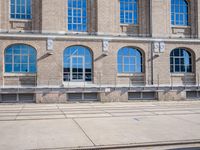 the building has many windows on it and is mostly empty with no people walking on the sidewalk