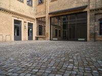 there is an empty courtyard between two buildings that are being converted into apartments and the doors are closed