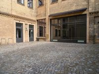 there is an empty courtyard between two buildings that are being converted into apartments and the doors are closed