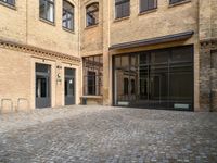 there is an empty courtyard between two buildings that are being converted into apartments and the doors are closed