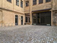 there is an empty courtyard between two buildings that are being converted into apartments and the doors are closed