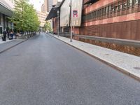 the empty street is lined with brick and pavement near buildings and a pedestrian crossing sign