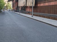 the empty street is lined with brick and pavement near buildings and a pedestrian crossing sign