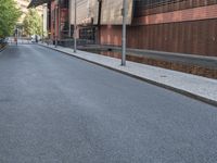 the empty street is lined with brick and pavement near buildings and a pedestrian crossing sign