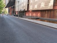 the empty street is lined with brick and pavement near buildings and a pedestrian crossing sign