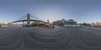 an empty boat in front of a bridge near a cityscape with skyscrapers