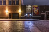 an empty alley with brick walkway and large poster of a woman standing at the door