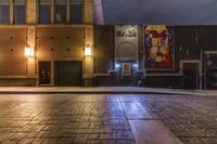 an empty alley with brick walkway and large poster of a woman standing at the door