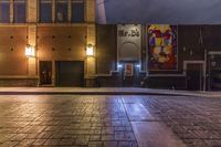 an empty alley with brick walkway and large poster of a woman standing at the door