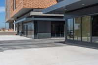 an empty brick building is seen with many glass doors and windows and lights on the wall