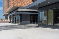 an empty brick building is seen with many glass doors and windows and lights on the wall