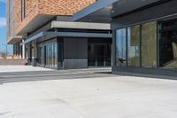 an empty brick building is seen with many glass doors and windows and lights on the wall