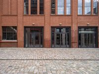 a view of an empty brick floor from the street with the entrance door open and no sign