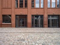 a view of an empty brick floor from the street with the entrance door open and no sign