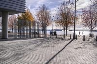 an empty brick pathway in front of a building with benches on the pavement near by